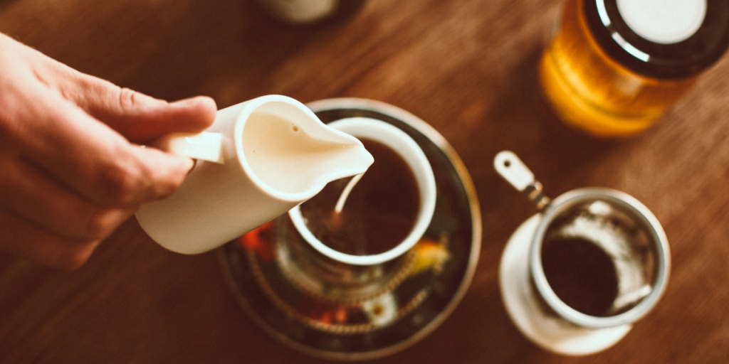 Someone pouring milk into a loose leaf tea