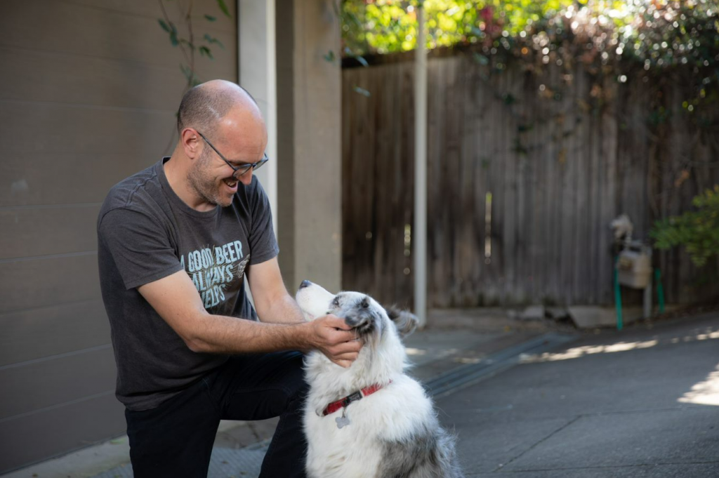 James Grugeon patting his border collie dog.