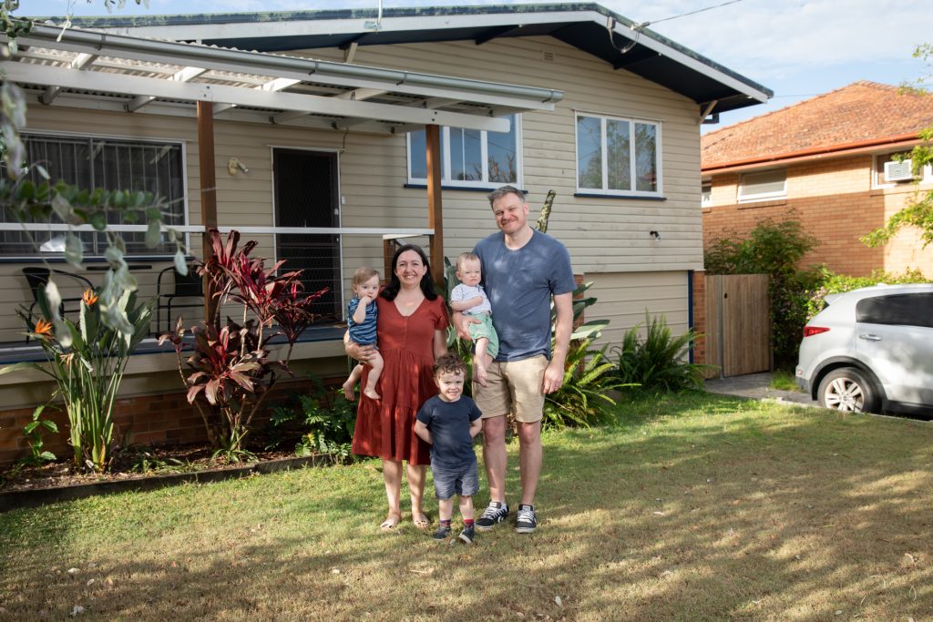 The Boyd family standing in front of their home in their front yard smiling at the camera.