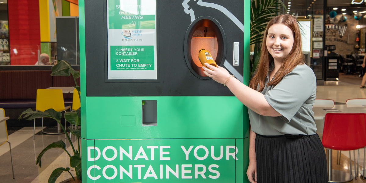 Woman placing container in Containers for Change drop-off machine in shopping centre.