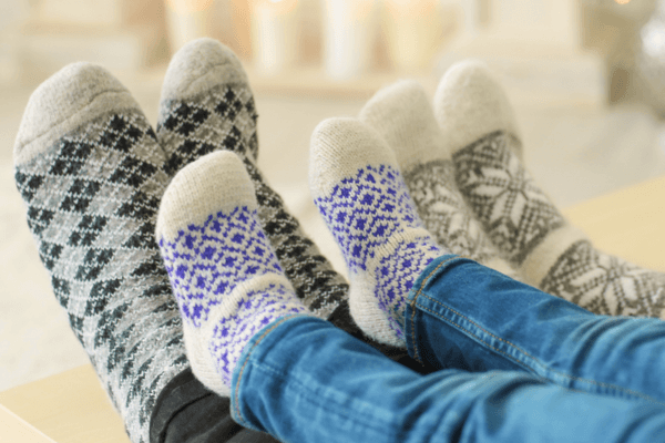 Three pairs of feet covered in thick woolen socks