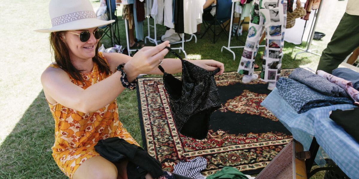 Woman rummaging through suitcase of pre-loved clothing