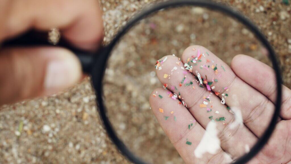 Someone looking at microplastics through a magnifying glass